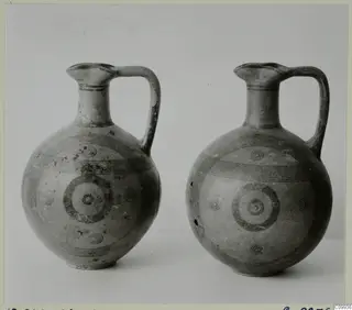 Two painted pottery jugs with single loop handles, standing side by side