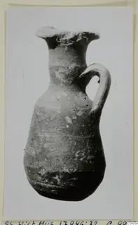 Pottery jug with a flared rim, narrow neck and single loop handle.
