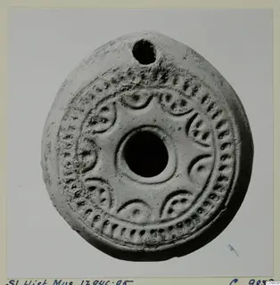 Terracotta lamp with a filling hole at the top and a ring of raised decoration around the central nozzle.