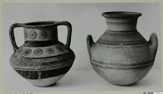 Two two-handled clay vessels side by side, the left one decorated with rows of concentric circles and dark bands.