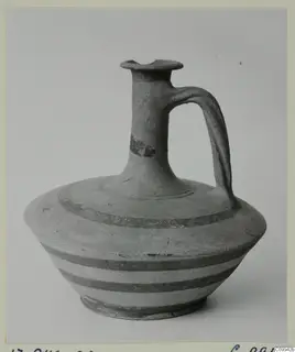 Cypro-Hell. II jug with a single loop handle and dark painted bands, shown against a plain grey background