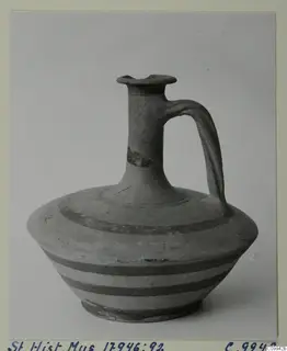 Jug with a flared mouth, one loop handle and dark horizontal bands, photographed against a plain background