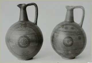 Two painted pottery jugs with a single handle, decorated with black concentric circles and horizontal bands.