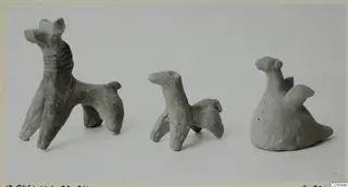 Three small terracotta animal figurines standing in a row against a plain background