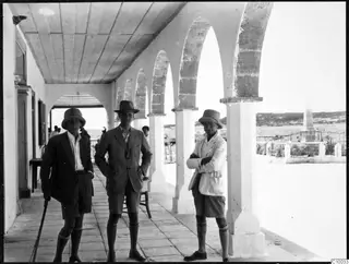 Westholm, Gjerstad and Sjöqvist standing in an arched cloister with hills behind