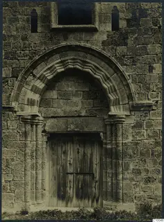Stone facade with a moulded arched doorway and a wooden plank door, Famagusta