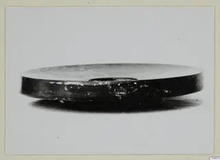 Black Glazed Ware bowl seen from the side against a plain background