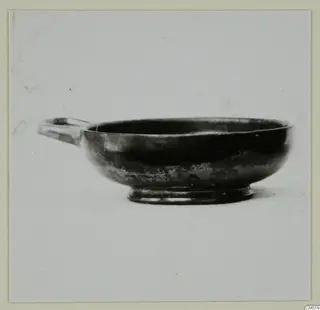 Black-glazed bowl with a single horizontal handle and a low ring foot.