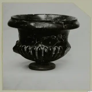 Black glazed bowl with a thick rim, lobed body with white-painted arches, and a ring foot.