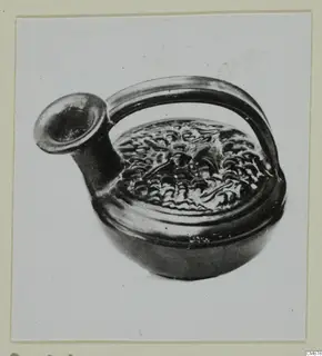 Black-glazed pottery vessel with a flaring spout, loop handle and relief decoration on the shoulder