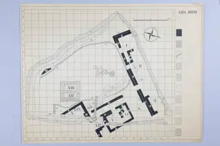 Plan drawing of Ayia Irini on a lettered and numbered grid, with walls shown in solid black, a scale bar and a compass rose.