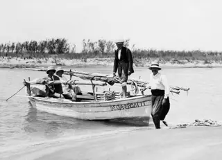 Small open boat with men in shallow water at Bogázi on the east coast