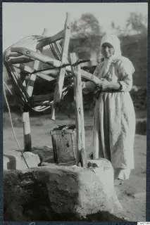 Woman in a white headscarf beside a well with a wooden windlass, Karpas peninsula