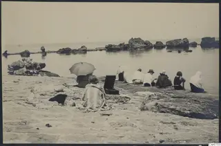 Expedition members seated on a rocky beach below Vouni, facing the sea