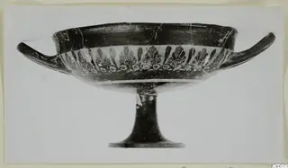 Stemmed bowl with two horizontal handles and a band of dark palmette motifs, seen from the side.