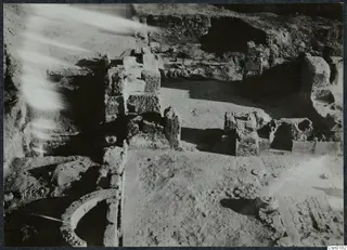 Excavated ruins at Salamis with stone walls, a paved floor and a curved wall in the foreground.