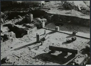 Excavated stone walls and a paved floor with scattered column drums at Salamis, Famagusta