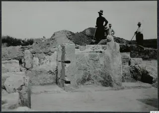 Excavated stone walls at Salamis, with three men in hats standing on a spoil heap behind them