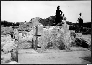 Excavation at Salamis showing stone walls, with three people in hats standing on a spoil heap behind