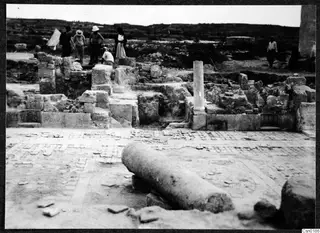 Excavated ruins at Salamis with a standing column shaft and a fallen column drum in the foreground, with people among the walls.