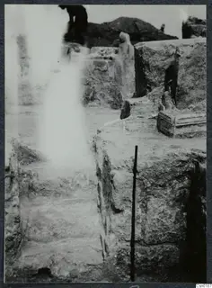 Wall and stairs at Salamis, with a ranging pole against the stonework and a partly visible person behind.