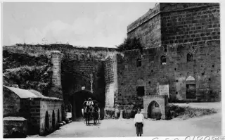 Stone gateway at Salamis near Famagusta, with a horse carriage passing through the arch and a boy standing in the road