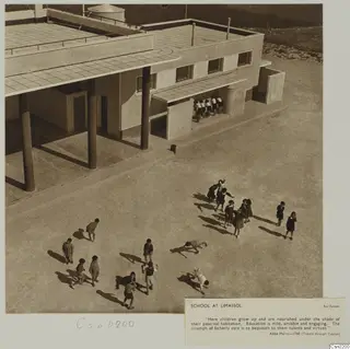 School at Limassol: children in a paved courtyard beside a flat-roofed building with round columns