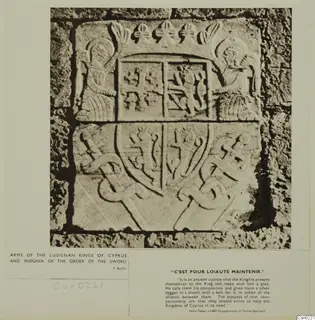 Carved stone arms of the Lusignan kings of Cyprus with a crown, shield and crossed sword forms, photographed in a stone wall