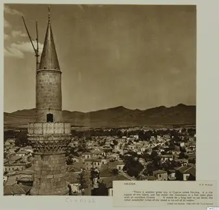 Nicosia: a stone tower with a conical top rises above rooftops, with mountains beyond