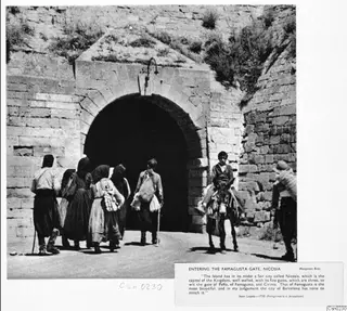 Several people and a donkey rider walk toward the arched Famagusta Gate in Nicosia