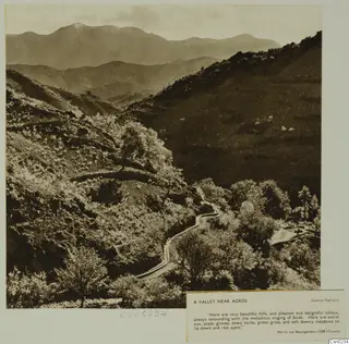 Valley near Agros with a winding road between wooded hills and distant mountains