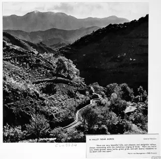 Valley near Agros with a winding road between wooded hillsides and distant mountains.
