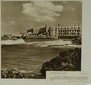 The Dome Hotel, Kyrenia, a multi-storey seafront hotel with waves breaking on dark rocks in the foreground.