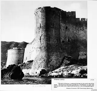 Kyrenia Castle, a large round stone tower and curtain wall rising from rocks above the sea, with a smaller round tower to the left.