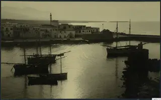 Harbour with whitewashed buildings, moored sailing boats and calm water seen from above