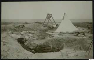 Workmen resting in the excavation at the palace at Vouni, with a white tent and the sea on the horizon.