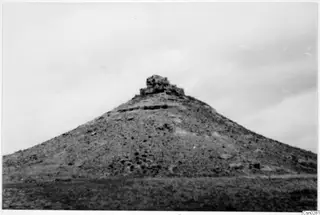 Conical hill with a ruined stone structure on its summit, sparse grass and scrub, near Nicosia
