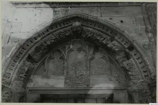 Carved stone doorway arch with foliage-decorated moulding and a head-shaped keystone, with a wooden door below, at Nicosia