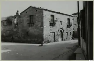 Stone building with an arched doorway and balconies on a Nicosia street, with a dog lying in the road.
