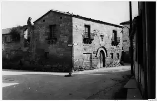 Stone building with an arched wooden doorway and iron balconies on a street in Nicosia, with a dog lying in the road.