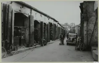 Street in Nicosia lined with arcaded shops, with a parked car, bicycles and people in the roadway.