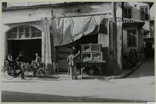 Street corner in Nicosia with a shop front, a bicycle and several people