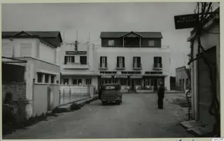 Street at Salamis, Famagusta, with a parked car, white multi-storey buildings and one standing person.