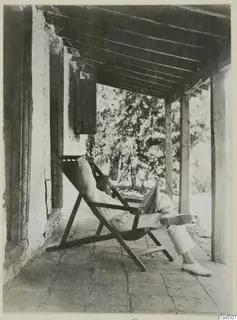 Erik Sjöqvist (?) reading a newspaper in a deck chair on a veranda