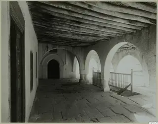 Covered arcaded gallery of a monastery building at Bellapais, with a timber ceiling, a wooden door and a railed stair