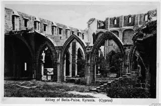 Abbey of Bella-Paise, Kyrenia: ruined stone walls with pointed arches open to the sky over a grassy court.