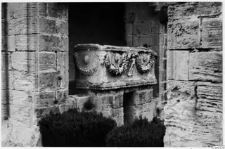 Carved stone chest with garland reliefs set in a recess between large stone-block walls, Monastery