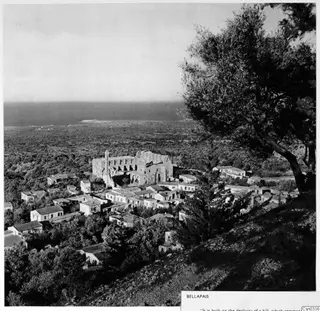Hillside village of Bellapais with a large ruined stone church, olive trees, and the plain and sea beyond