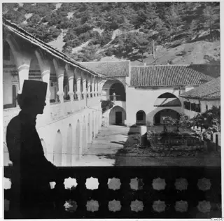Courtyard of Kykko Monastery with an arcaded gallery, tiled roofs and a pine-covered hillside behind