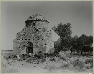 Monastery building with a stone dome and arched doorway, with trees beside it